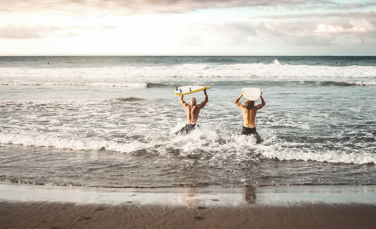 Happy fit friends having fun surfing on sunset time